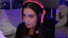 a woman wearing pink headphones is sitting in front of a computer monitor .