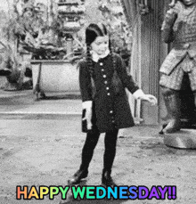 a little girl in a black dress is dancing in a room with the words `` happy wednesday '' written on it .