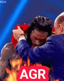 a man in a suit is being hugged by another man with the word agr on the bottom