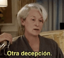 a woman is sitting on a couch and says otra decepcion .