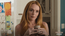a woman is holding a cup of coffee in front of a disney freakier friday poster