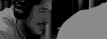 a man with a beard is wearing headphones and smiling in a black and white photo .