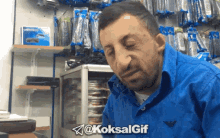 a man in a blue shirt is making a funny face in front of a display of remotes