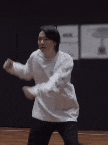 a man in a white sweater is dancing on a wooden floor .