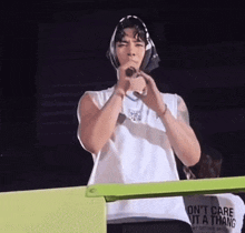 a man singing into a microphone wearing a white shirt that says " don 't care it a thang "