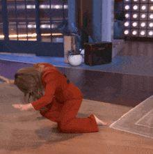 a woman in a red jumpsuit is kneeling down