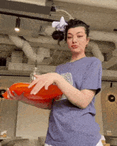 a woman wearing a t-shirt that says ' nasa ' on it is holding an orange tray
