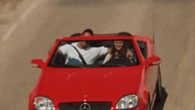 a man and woman are in a red mercedes