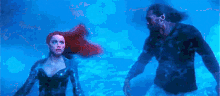 a man and a woman are standing in the water .