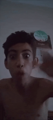 a shirtless young boy is making a funny face in front of a calendar .