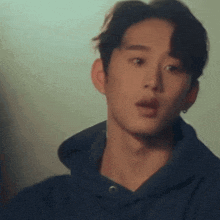 a young man wearing a blue hoodie and earrings is looking at the camera .