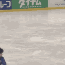 a person is skating on an ice rink with a green sign that says synergice