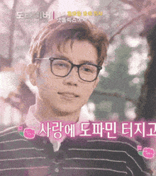 a young man wearing glasses and a striped shirt is smiling in front of a cherry blossom tree