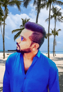 a man wearing sunglasses and a blue shirt is standing on a beach