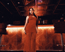 a woman in a red dress standing in front of a bar