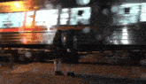 a blurry picture of two people standing in front of a train that says ' a ' on it