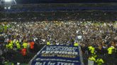 a large crowd of people are gathered around a sign that says " no 1 for tyres "