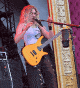 a woman playing a guitar and singing into a microphone