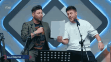 two men singing in front of a screen that says rtve