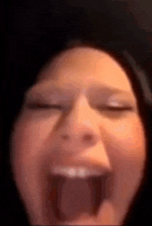 a close up of a woman screaming with her mouth open .