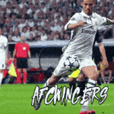a soccer player wearing a fly emirates jersey is kicking a ball