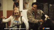 a man and a woman are petting a cat in a cage with a nbc logo in the corner