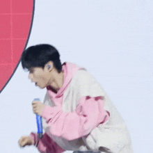a young man in a pink hoodie is standing in front of a red heart .