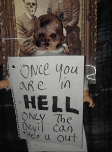 a doll is holding a piece of paper that says once you are in hell only the devil can help you out