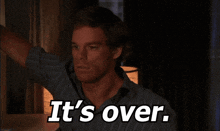 a man in a blue shirt says it 's over in a dark room