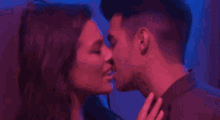 a man and a woman are kissing in a dark room in a red and blue light .
