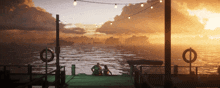 a couple sits on a dock looking out over the ocean at sunset