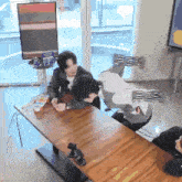 two people sitting at a table with one laying on the floor and another laying on the table