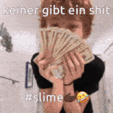 a person holding a bunch of money in front of their face with the caption keiner gibt ein shit #slime