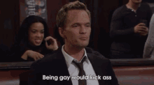a man in a suit and tie is holding a glass and says being gay would kick ass