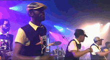 a man wearing a shirt that says ' venus ' on it stands in front of a drum set