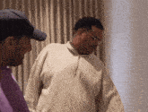 two men standing next to each other one wearing glasses and a purple shirt