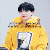 a young man wearing a yellow hoodie with the words como cuando eres de igna eres feliz con elle y la ama