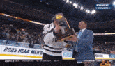 a hockey player is holding a trophy in front of a banner that says 2025 ncaa men 's