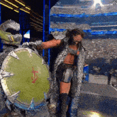 a woman in a costume is holding a large green shield