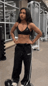 a woman standing in a gym with her hands on her hips wearing a gymshark top