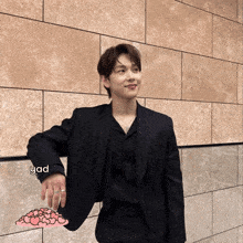 a man in a black suit is leaning against a wall with the word yad written on it