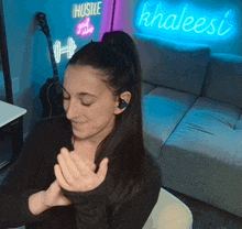 a woman clapping in front of a neon sign that says hustle and good vibes