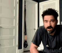 a man with a beard wearing a black shirt with the word adidas on it