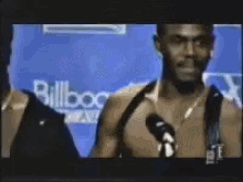 a man is talking into a microphone in front of a wall that says billboard