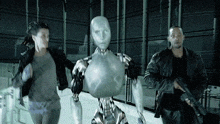 a man holding a gun stands next to a woman and a silver robot