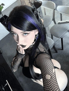 a woman with purple hair is taking a selfie in front of a glass table