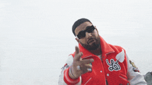 a man wearing sunglasses and a varsity jacket with the letter ls on it