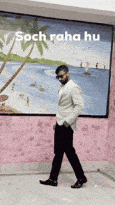 a man in a suit walks in front of a painting that says soch raha hu