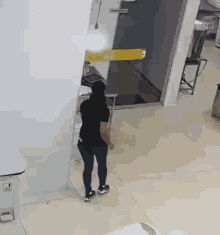 a woman in a black shirt is standing in a room with a yellow door .