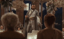 a man in a robe stands in front of a crowd with the words joy behind him
